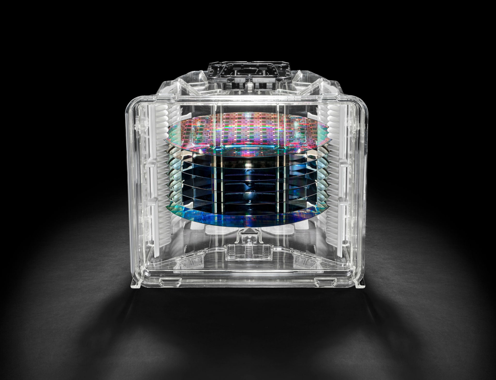 Stack of iridescent semiconductor wafers enclosed in a transparent protective container