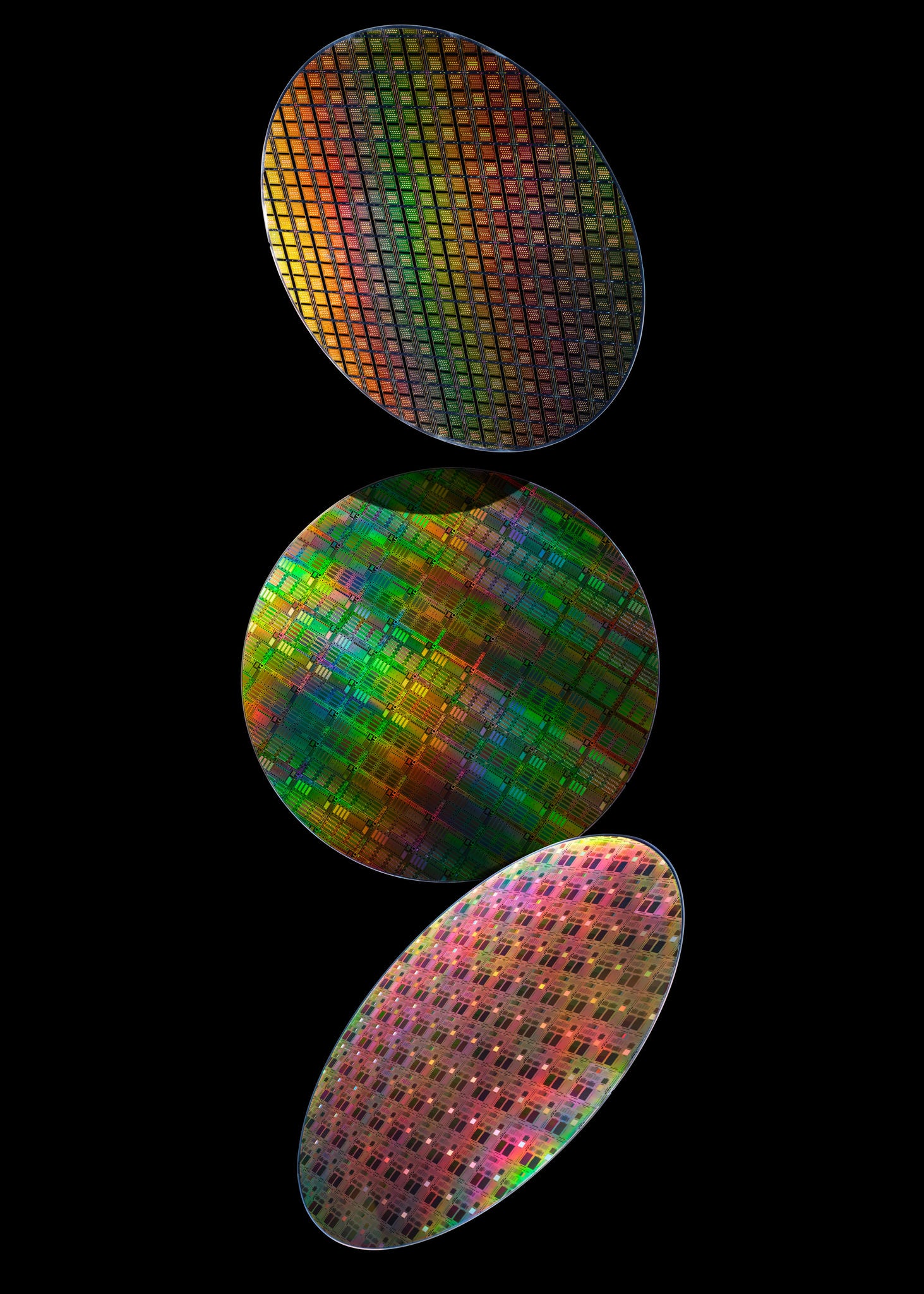 Three iridescent semiconductor wafers with visible chip patterns against a black background